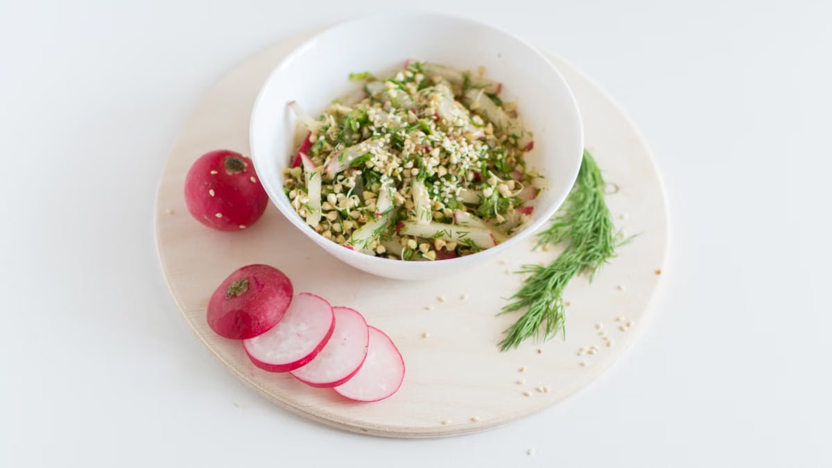 A healthy vegan salad with buckwheat, radish, and dill garnished with sesame seeds.