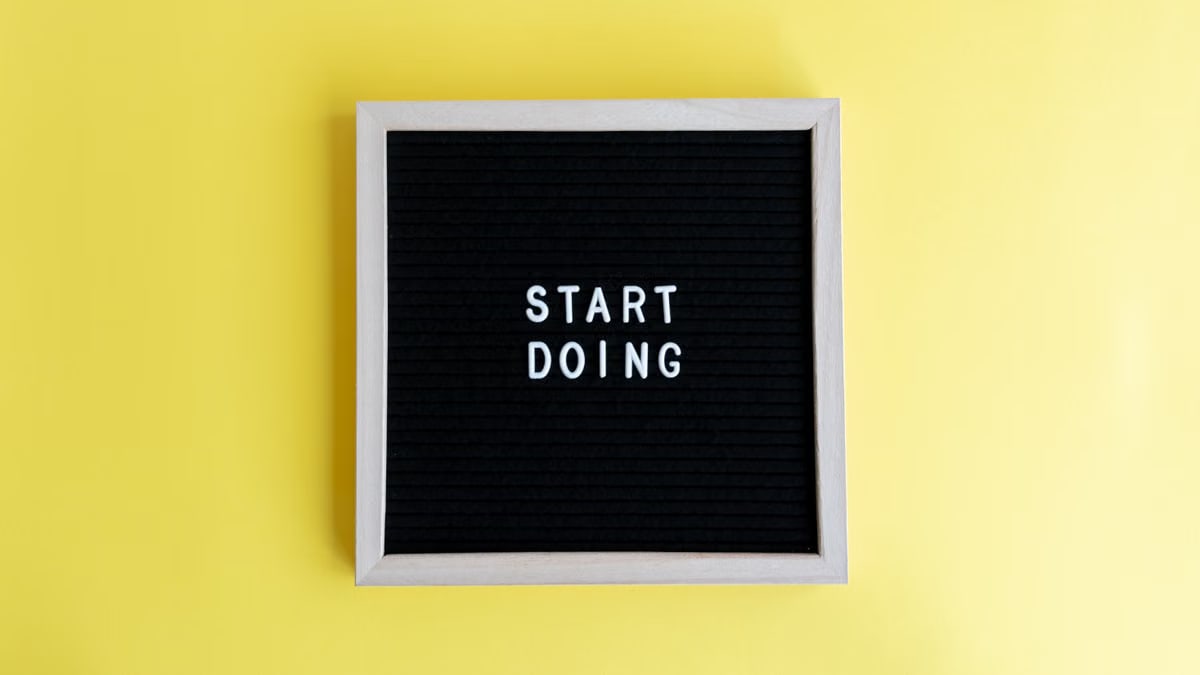 Black message board with 'Start Doing' on a bright yellow background for inspiration.